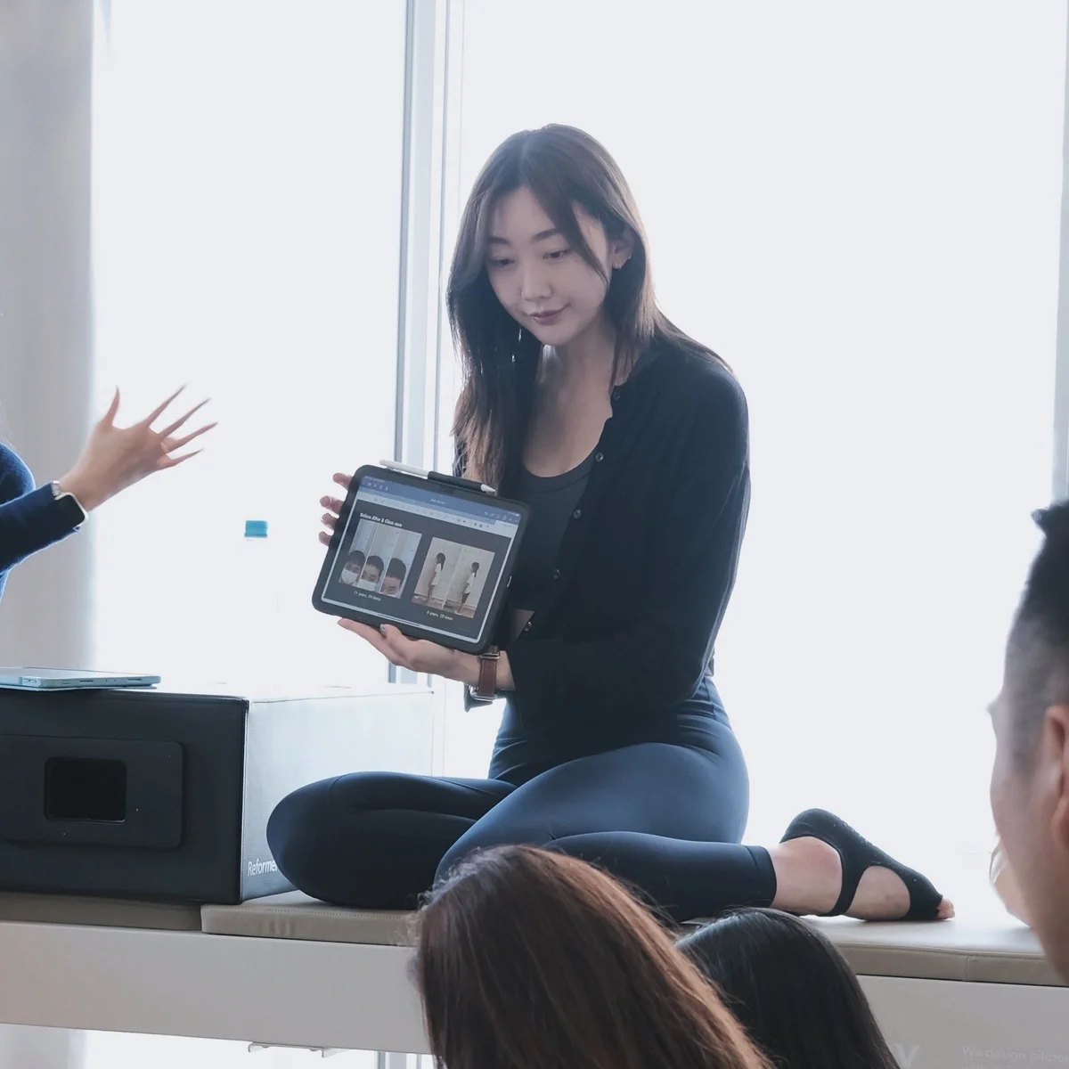 한국 필라테스 스튜디오 — 강사가 신규 수강생의 자세 평가를 아이패드로 보여주는 장면